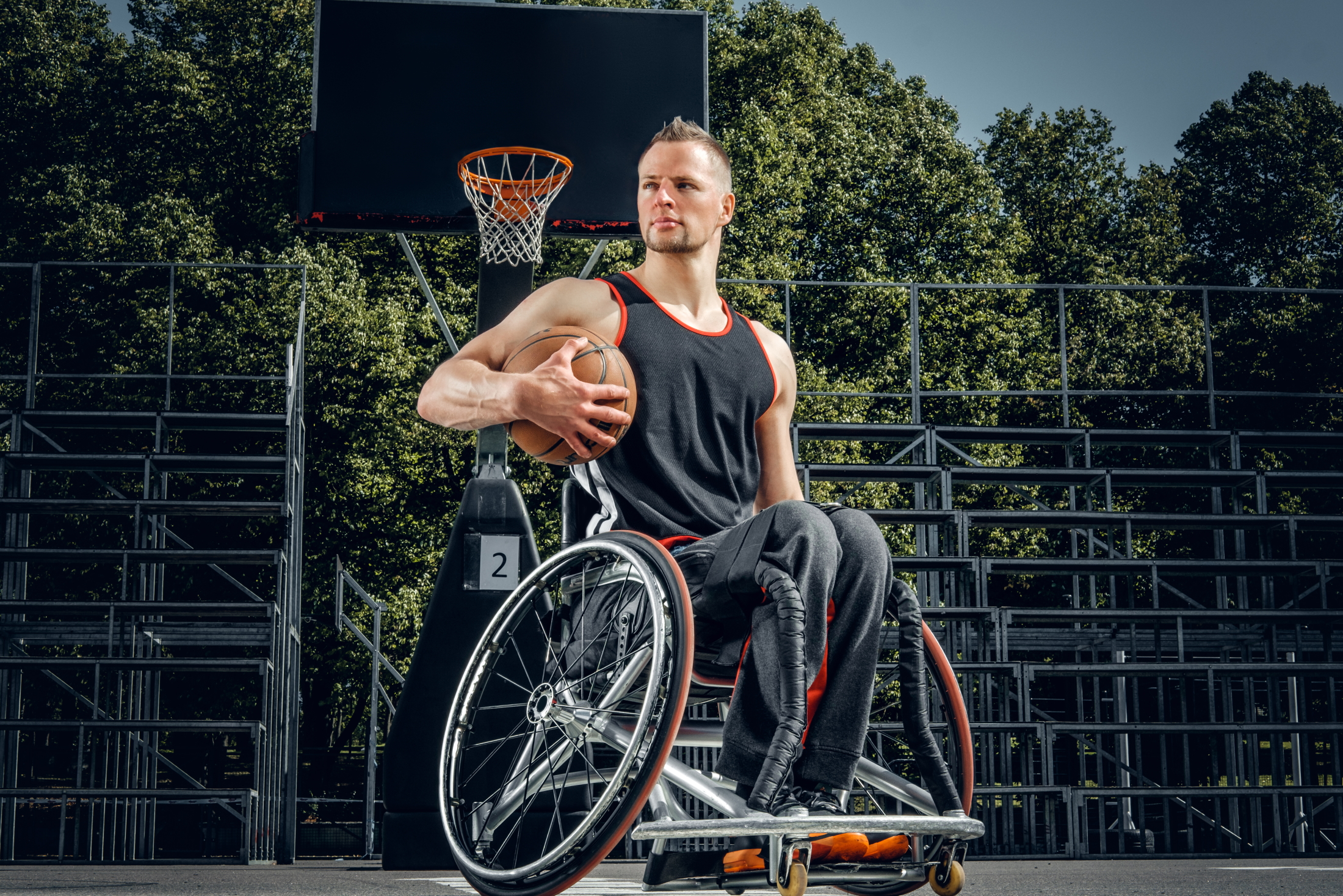 Portrait of cripple basketball player in wheelchair on open gaming ground.